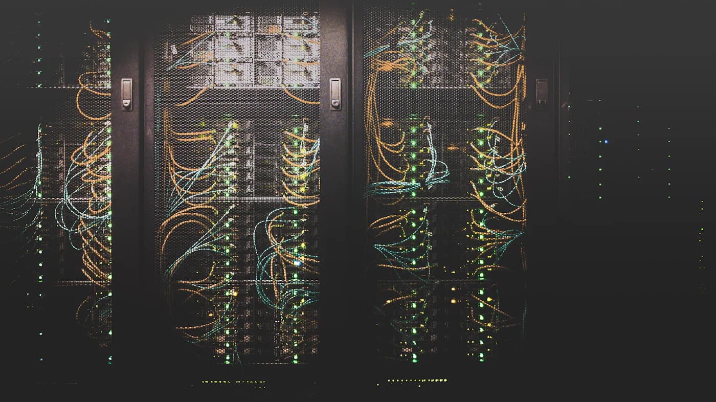Serverracks verbonden met oranje en blauwgroene bekabeling in een donker datacenter